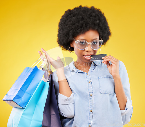 Image of Shopping bag, retail credit card and portrait black woman with sales product, studio fashion deal or mall store attitude. Commerce market, discount gift or female customer biting on yellow background