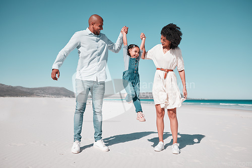 Image of Father, mother and daughter with swing at beach, holding hands and support for funny game with smile. Happy family, ocean and vacation with man, woman and girl for freedom, sunshine or bond with love