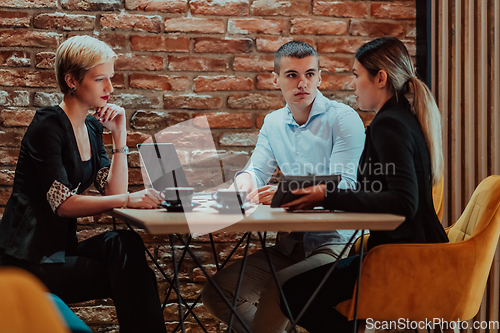 Image of Happy businesspeople smiling cheerfully during a meeting in a coffee shop. Group of successful business professionals working as a team in a multicultural workplace.