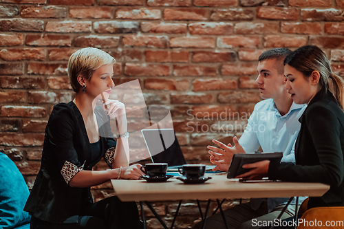 Image of Happy businesspeople smiling cheerfully during a meeting in a coffee shop. Group of successful business professionals working as a team in a multicultural workplace.