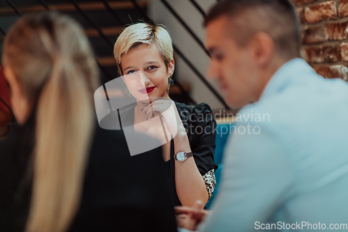 Image of Happy businesspeople smiling cheerfully during a meeting in a coffee shop. Group of successful business professionals working as a team in a multicultural workplace.