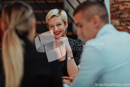 Image of Happy businesspeople smiling cheerfully during a meeting in a coffee shop. Group of successful business professionals working as a team in a multicultural workplace.