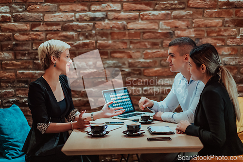 Image of Happy businesspeople smiling cheerfully during a meeting in a coffee shop. Group of successful business professionals working as a team in a multicultural workplace.