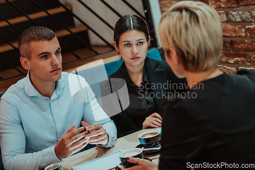 Image of Happy businesspeople smiling cheerfully during a meeting in a coffee shop. Group of successful business professionals working as a team in a multicultural workplace.