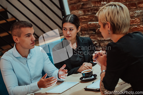 Image of Happy businesspeople smiling cheerfully during a meeting in a coffee shop. Group of successful business professionals working as a team in a multicultural workplace.