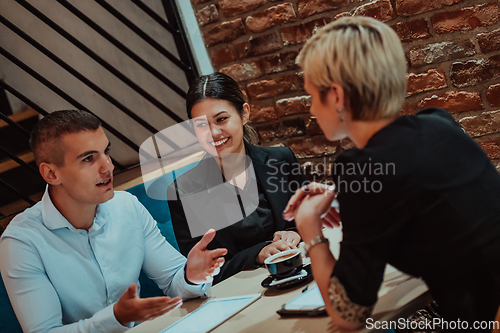 Image of Happy businesspeople smiling cheerfully during a meeting in a coffee shop. Group of successful business professionals working as a team in a multicultural workplace.