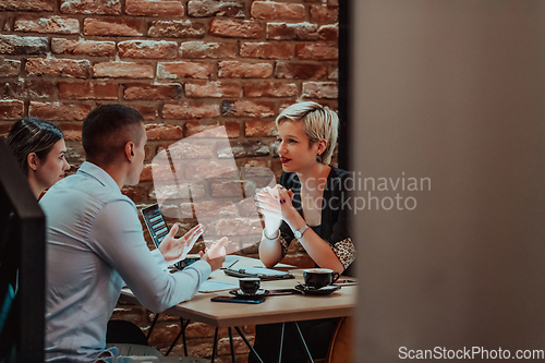 Image of Happy businesspeople smiling cheerfully during a meeting in a coffee shop. Group of successful business professionals working as a team in a multicultural workplace.