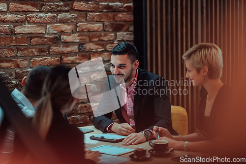 Image of Happy businesspeople smiling cheerfully during a meeting in a coffee shop. Group of successful business professionals working as a team in a multicultural workplace.