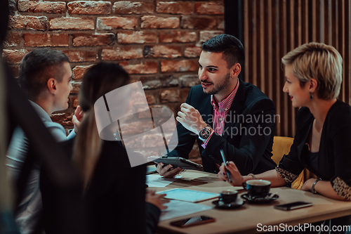 Image of Happy businesspeople smiling cheerfully during a meeting in a coffee shop. Group of successful business professionals working as a team in a multicultural workplace.