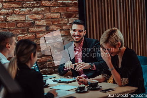 Image of Happy businesspeople smiling cheerfully during a meeting in a coffee shop. Group of successful business professionals working as a team in a multicultural workplace.