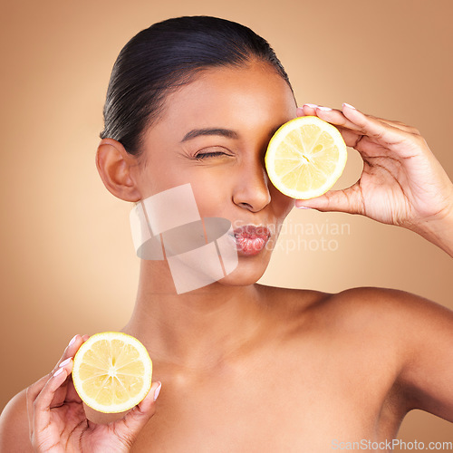 Image of Indian woman, skincare and lemon in studio with health, wellness or fruit treatment by brown background. Asian model girl, young and happy with organic citrus fruits for health, cosmetic or skin glow