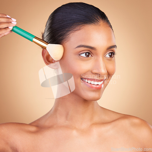 Image of Makeup, beauty and product with indian woman and brush in studio for foundation, blush and self care. Glow, cosmetics and facial with model isolated on brown background for shine, clean or confidence