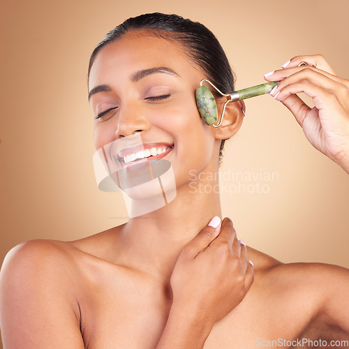 Image of Facial, massage and skincare with a model woman in studio on a brown background for natural antiaging beauty. Wellness, luxury and product with an attractive young female using a roller for skin lift