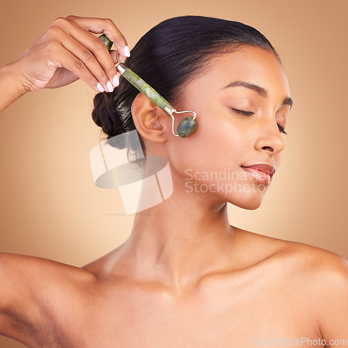 Image of Woman, beauty and derma roller with face, calm with facial massage and skincare on studio background. Cosmetic tools, healthy skin glow and female with eyes closed, jade quartz and crystal with peace