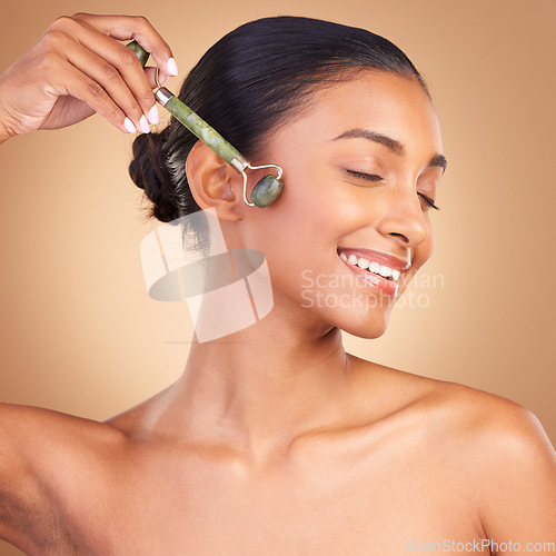 Image of Woman, beauty and derma roller with face, happy with facial massage and skincare on studio background. Cosmetic tools, healthy skin glow and female smile with eyes closed, jade quartz and crystal