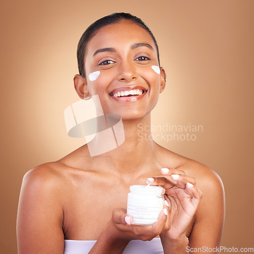 Image of Indian woman, skincare cream and jar in hands for portrait, health and wellness by brown background. Young model, lotion product and studio with aesthetic, dermatology and clean with cosmetic beauty