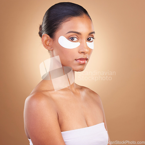 Image of Skincare, eye patch and beauty with Indian woman for facial, spa treatment and glow. Self care, cosmetics and hydration with female model isolated on brown background for mask, product and youth