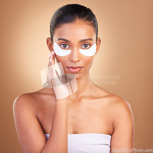Image of Beauty, eye patch and portrait of Indian woman in studio for facial, spa treatment and glow. Self care, cosmetics and hydration with female model on brown background for mask, product and youth