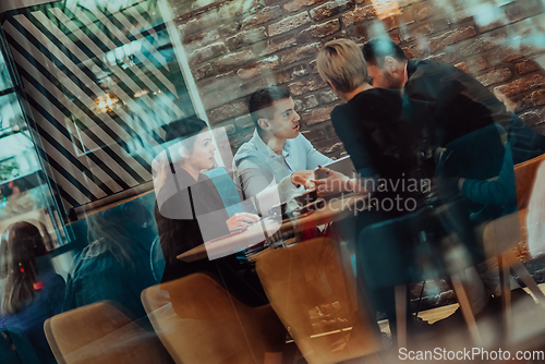 Image of Happy businesspeople smiling cheerfully during a meeting in a coffee shop. Group of successful business professionals working as a team in a multicultural workplace.