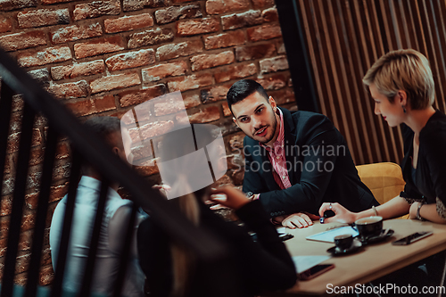 Image of Happy businesspeople smiling cheerfully during a meeting in a coffee shop. Group of successful business professionals working as a team in a multicultural workplace.