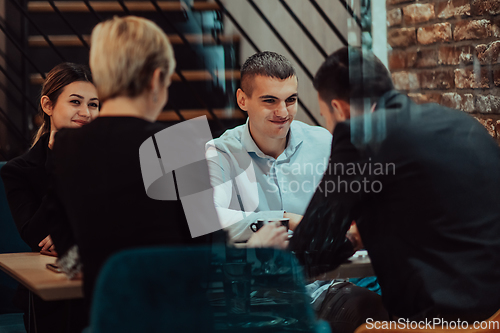 Image of Happy businesspeople smiling cheerfully during a meeting in a coffee shop. Group of successful business professionals working as a team in a multicultural workplace.