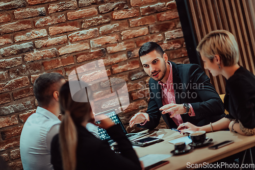 Image of Happy businesspeople smiling cheerfully during a meeting in a coffee shop. Group of successful business professionals working as a team in a multicultural workplace.