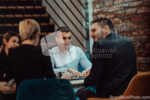 Image of Happy businesspeople smiling cheerfully during a meeting in a coffee shop. Group of successful business professionals working as a team in a multicultural workplace.