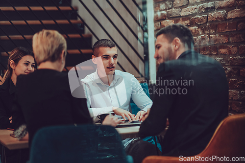 Image of Happy businesspeople smiling cheerfully during a meeting in a coffee shop. Group of successful business professionals working as a team in a multicultural workplace.