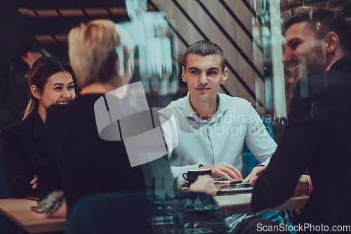 Image of Happy businesspeople smiling cheerfully during a meeting in a coffee shop. Group of successful business professionals working as a team in a multicultural workplace.