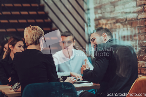 Image of Happy businesspeople smiling cheerfully during a meeting in a coffee shop. Group of successful business professionals working as a team in a multicultural workplace.