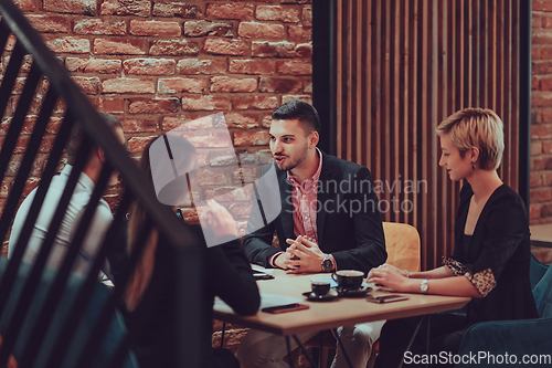 Image of Happy businesspeople smiling cheerfully during a meeting in a coffee shop. Group of successful business professionals working as a team in a multicultural workplace.