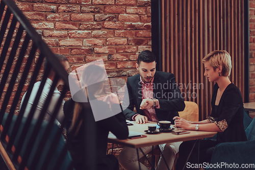 Image of Happy businesspeople smiling cheerfully during a meeting in a coffee shop. Group of successful business professionals working as a team in a multicultural workplace.