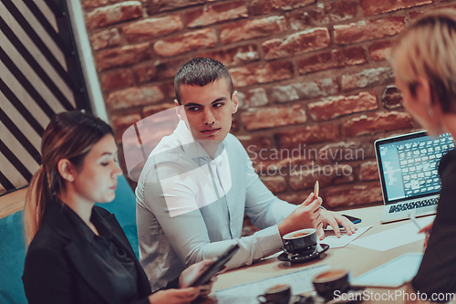 Image of Happy businesspeople smiling cheerfully during a meeting in a coffee shop. Group of successful business professionals working as a team in a multicultural workplace.