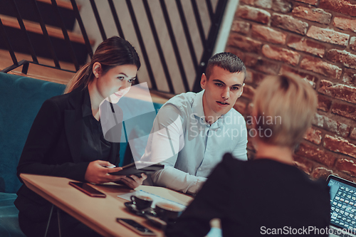 Image of Happy businesspeople smiling cheerfully during a meeting in a coffee shop. Group of successful business professionals working as a team in a multicultural workplace.