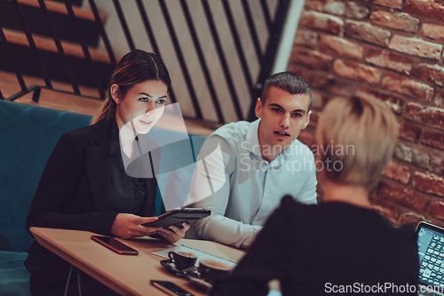 Image of Happy businesspeople smiling cheerfully during a meeting in a coffee shop. Group of successful business professionals working as a team in a multicultural workplace.