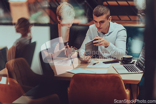 Image of Photo through the glass of a group of business people sitting in a cafe and discussing business plans and ideas for new online commercial services