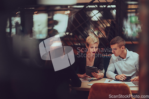 Image of Photo through the glass of a group of business people sitting in a cafe and discussing business plans and ideas for new online commercial services