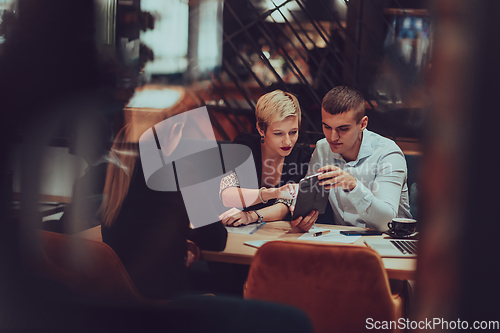 Image of Photo through the glass of a group of business people sitting in a cafe and discussing business plans and ideas for new online commercial services