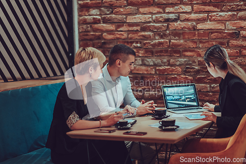 Image of Happy businesspeople smiling cheerfully during a meeting in a coffee shop. Group of successful business professionals working as a team in a multicultural workplace.