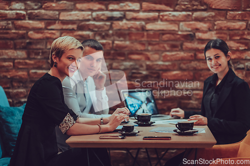 Image of Happy businesspeople smiling cheerfully during a meeting in a coffee shop. Group of successful business professionals working as a team in a multicultural workplace.