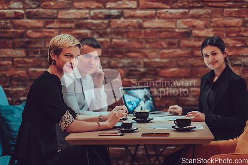 Image of Happy businesspeople smiling cheerfully during a meeting in a coffee shop. Group of successful business professionals working as a team in a multicultural workplace.