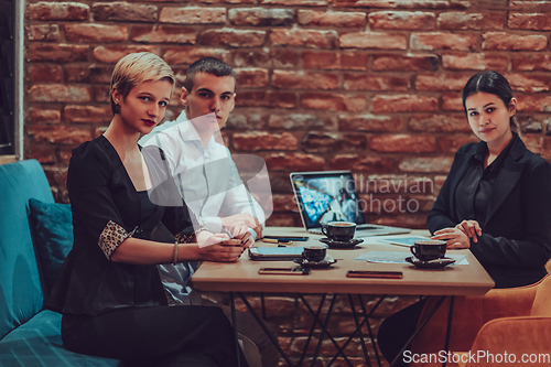 Image of Happy businesspeople smiling cheerfully during a meeting in a coffee shop. Group of successful business professionals working as a team in a multicultural workplace.