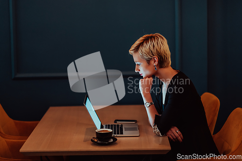 Image of Businesswoman sitting in a cafe while focused on working on a laptop and participating in an online meetings. Selective focus.