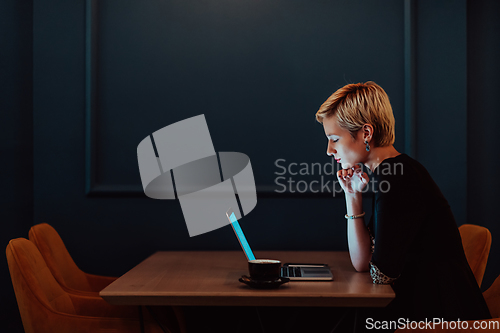 Image of Businesswoman sitting in a cafe while focused on working on a laptop and participating in an online meetings. Selective focus.