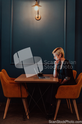 Image of Businesswoman sitting in a cafe while focused on working on a laptop and participating in an online meetings. Selective focus.