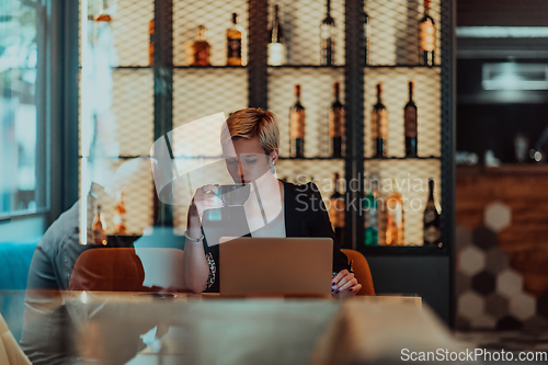 Image of Businesswoman sitting in a cafe while focused on working on a laptop and participating in an online meetings. Selective focus.