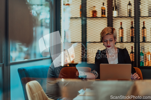 Image of Businesswoman sitting in a cafe while focused on working on a laptop and participating in an online meetings. Selective focus.