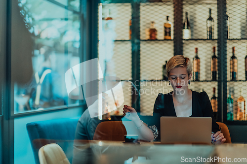 Image of Businesswoman sitting in a cafe while focused on working on a laptop and participating in an online meetings. Selective focus.