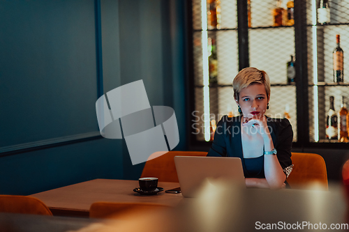 Image of Businesswoman sitting in a cafe while focused on working on a laptop and participating in an online meetings. Selective focus.