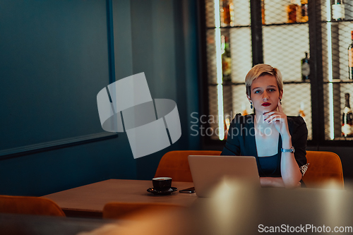 Image of Businesswoman sitting in a cafe while focused on working on a laptop and participating in an online meetings. Selective focus.